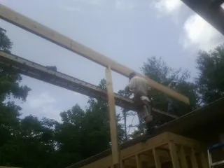 Carpenter setting a ridge beam over a new addition frame — Ice Dam Removal by Roofing Brothers in Rayle