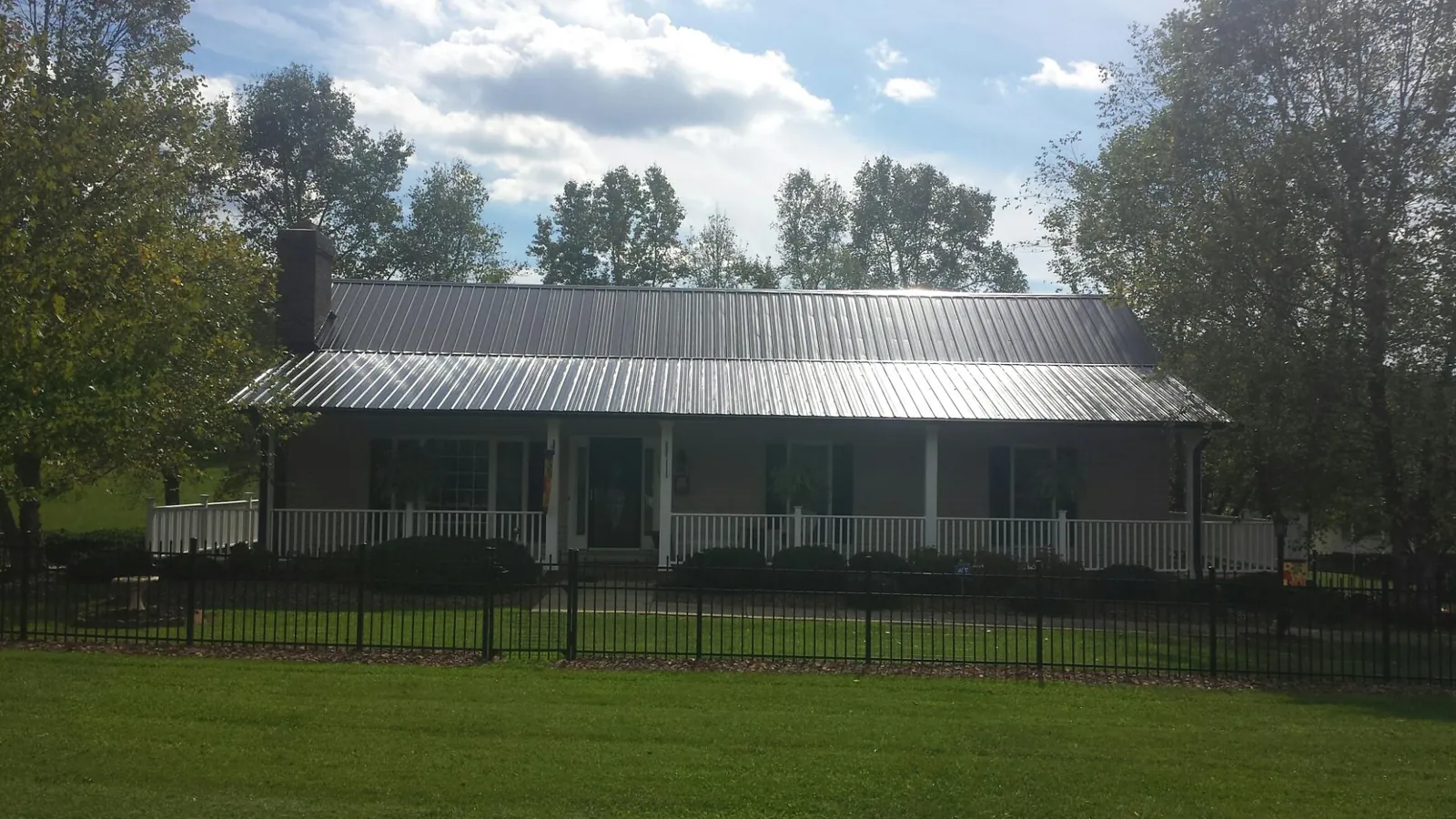 Gray metal roof on a brick ranch with a full width front porch — Gutter Guard Installation work by our crew in Rayle